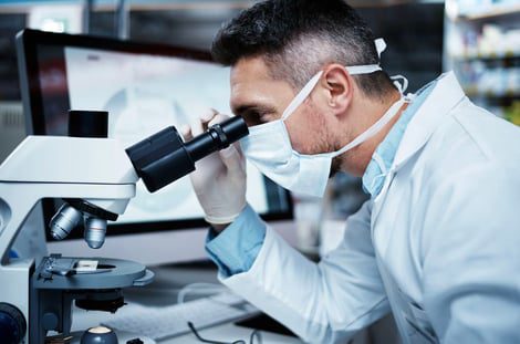 Person in lab coat using microscope